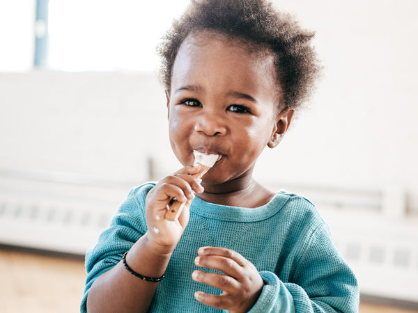 close up of a toddler with a spoonful of yogurt in their mouth