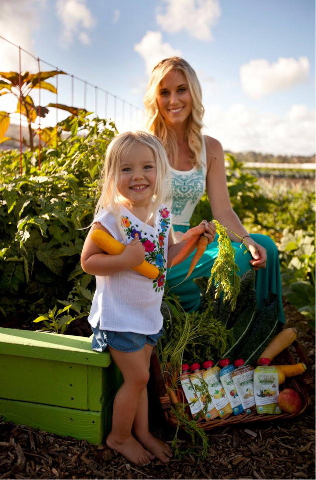Mother and daughter in a field with Ofarm products stacked nearby.