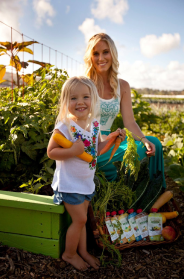 Mother and daughter in a field with Ofarm products stacked nearby.