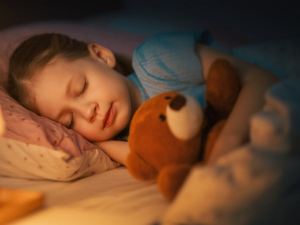 close up of a child cuddling with a teddy bear in bed