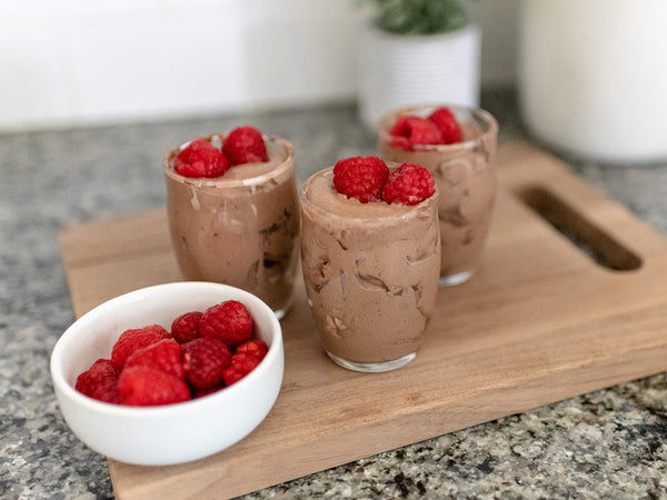 Whipped Raspberry Chocolate Mousse in cups, alongside a bowl of raspberries