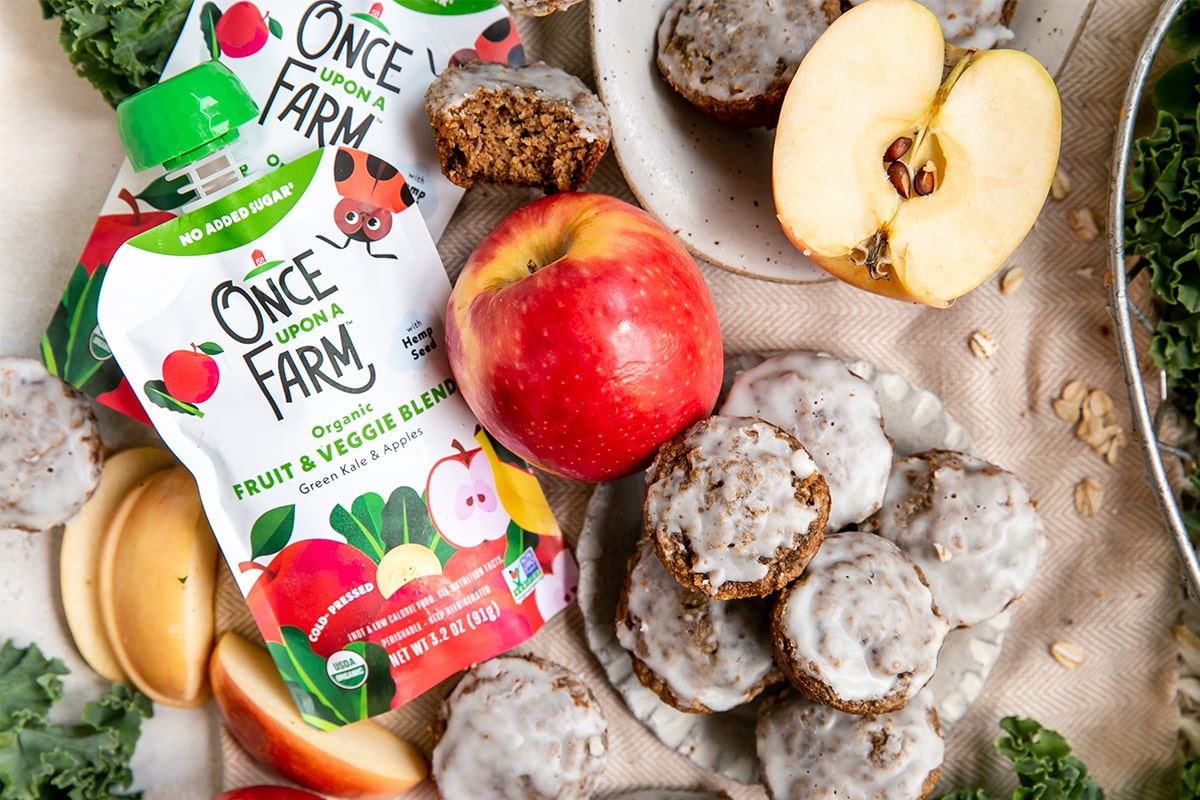 apple donut holes, next to two once upon a farm green kale & apples pouches and two fresh apples