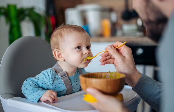 baby being spoon-fed baby food puree