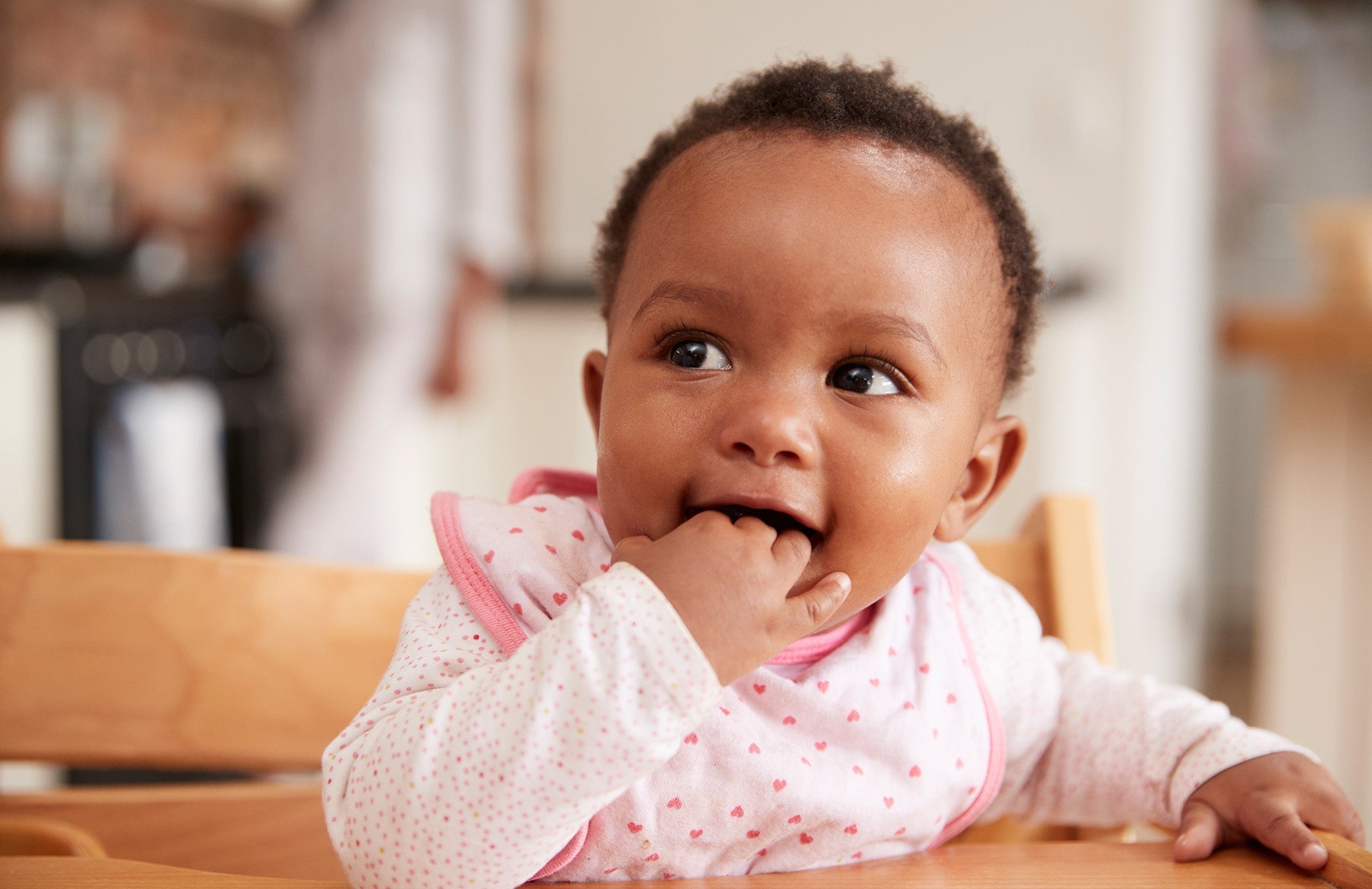 baby in high chair with hand in mouth