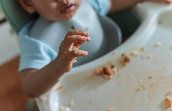close up of a toddler in a high chair with a messy tray