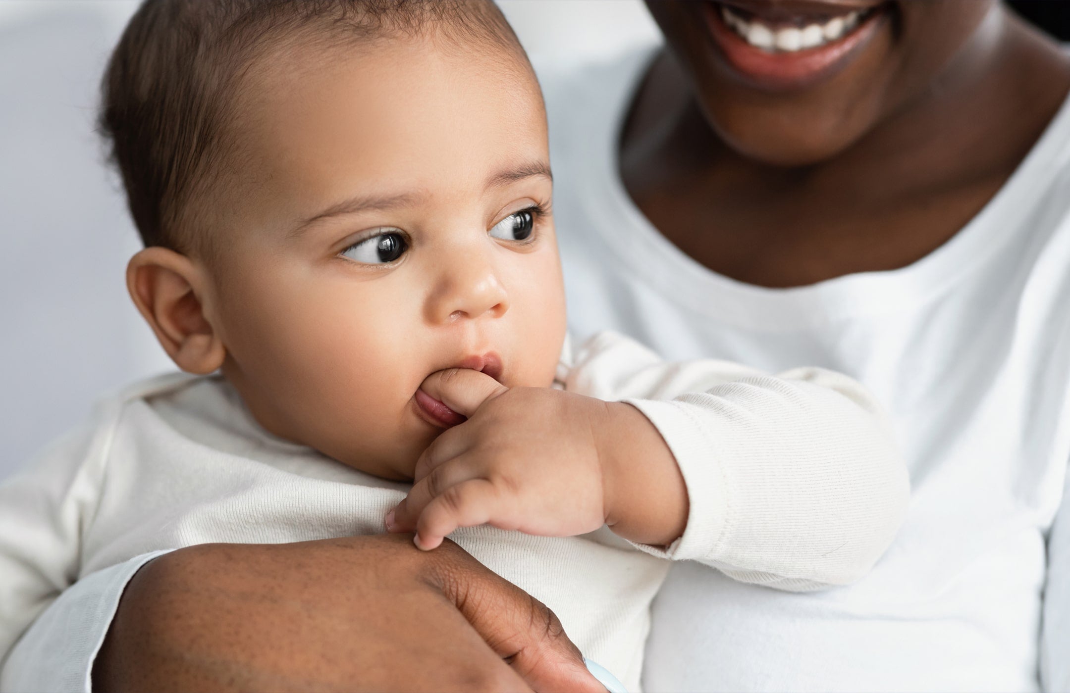 mom holding baby, who has their hand in their mouth