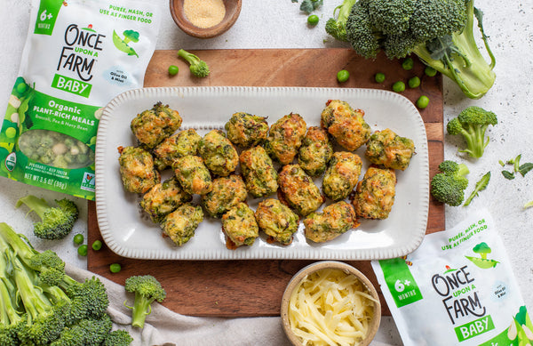 Broccoli cheese tots on a platter, surrounded by fresh broccoli and the Once Upon a Farm Broccoli, Pea and Navy Bean Meal packaging
