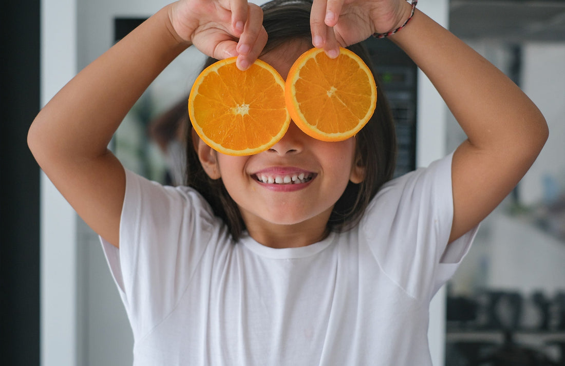 child holding orange slices over her eyes
