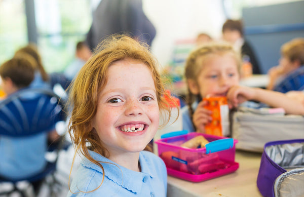 young girl smiling in school cafeteria 