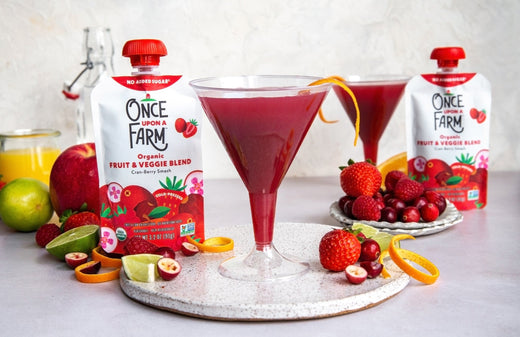 cranberry mocktails in plastic martini glasses, surrounded by fresh fruit and Once Upon a Farm pouches