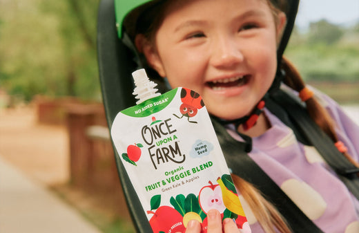 girl on bike, holding a Once Upon a Farm pouch