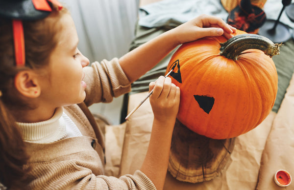 girl painting a face on a pumpkin