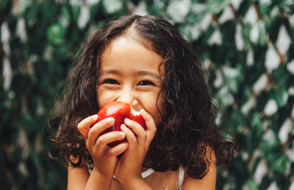 close up of a girl with curly hair biting into an apple