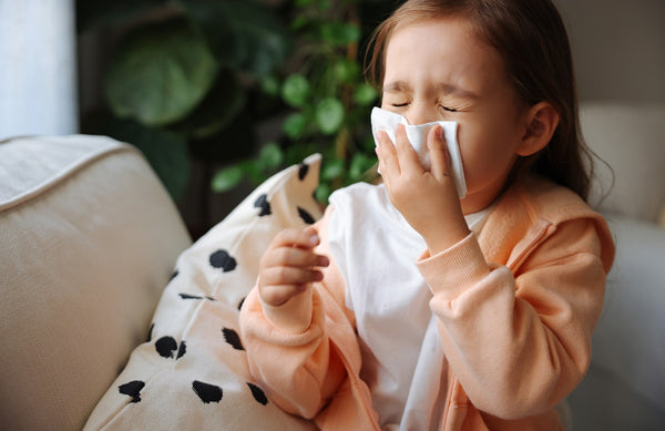 child blowing her nose into a tissue