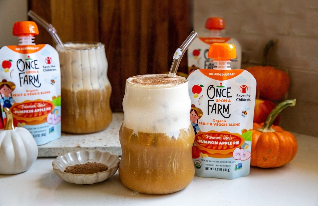 two glasses with pumpkin cream cold foam on top of iced coffee. once upon a farm farm pumpkin apple pie pouches are next to them