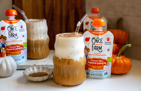 two glasses with pumpkin cream cold foam on top of iced coffee. once upon a farm farm pumpkin apple pie pouches are next to them