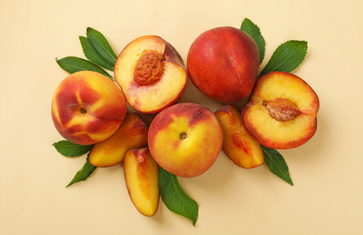 whole peaches, peach halves, and peach slices arranged in an aesthetic way