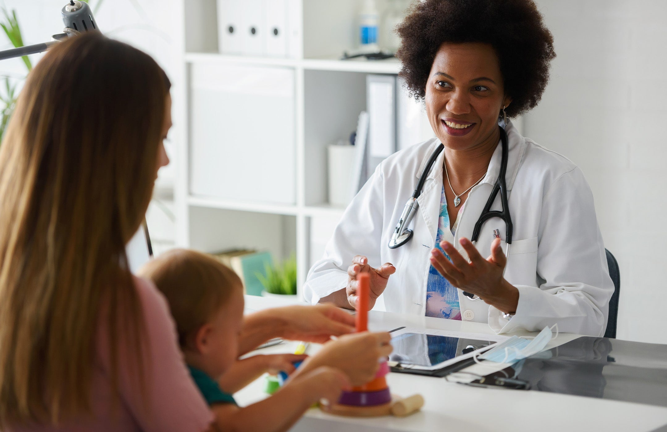 mom holding baby and talking with pediatrician in office