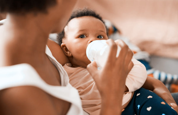 close up of a mom bottle-feeding a baby