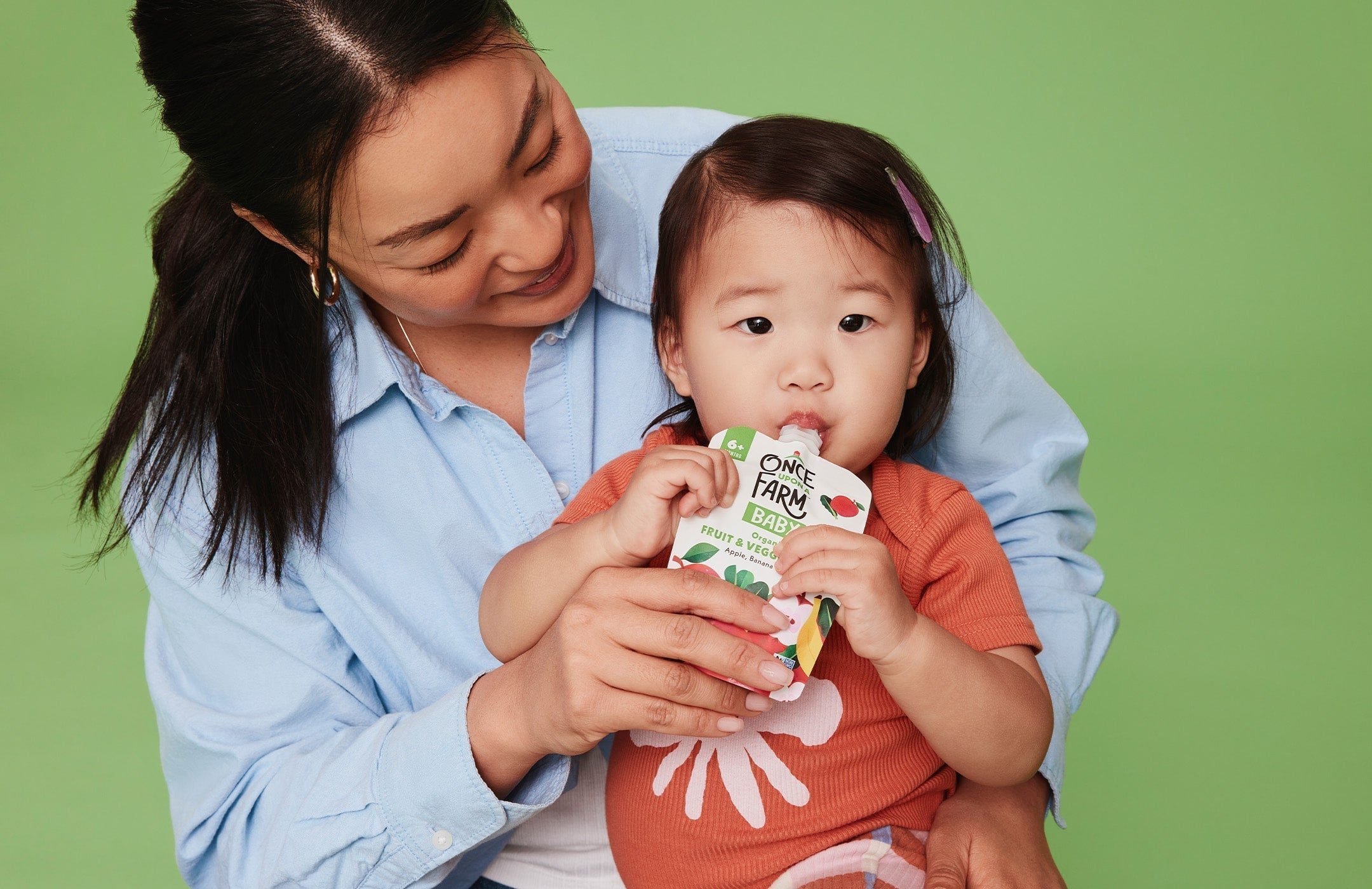 mother helping baby eat a Once Upon a Farm pouch