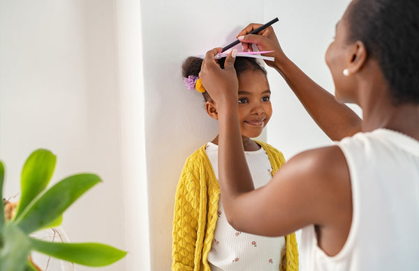 mom measuring daughter's height against a wall