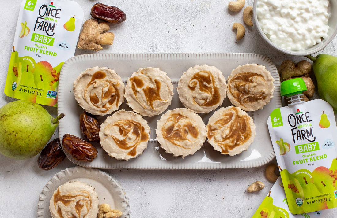 mini no-bake pear cheesecakes on a serving plate, next to two Once Upon a Farm Pear Fruit Blend pouches and various ingredients