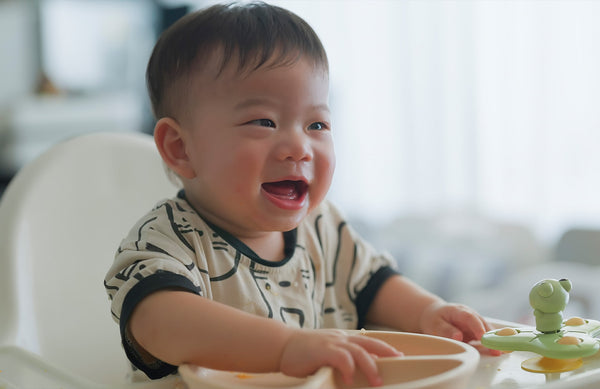 baby sitting in a highchair and smiling with an empty plate