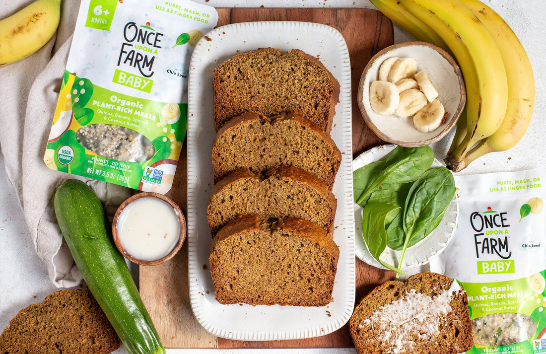 a loaf of sliced banana zucchini bread on a tray, surrounded by fresh ingredients and a Once Upon a Farm Plant-Rich Meal