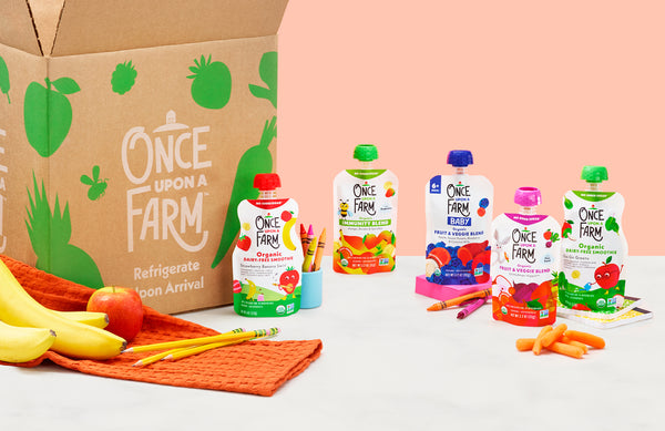 Once Upon a Farm subscription box, with various Once Upon a Farm pouches and fresh fruits and veggies next to it