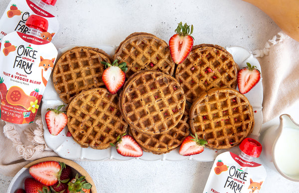 tray of strawberry waffles, surrounded by fresh strawberries and Once Upon a Farm Strawberry Patch Fruit & Veggie Blend pouches