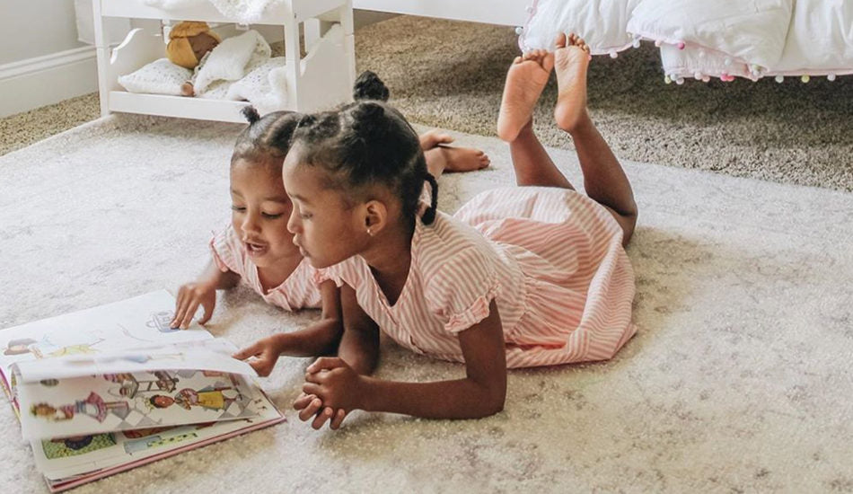 Image of two young girls reading a book.