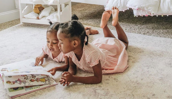 Image of two young girls reading a book.