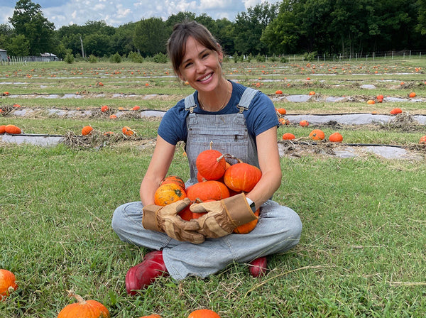 Farmer Jen on the farm holding pumpkins, that inspired her Pumpkin Oatmeal Cookie recipe. 
