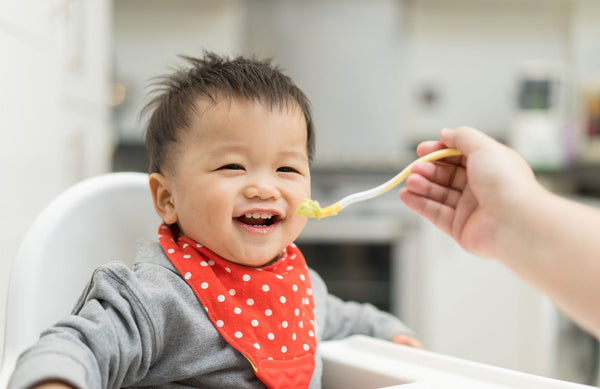 Mom feeding her baby's first foods using tips for starting solids.