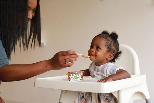 Mom feeding her baby organic, cold-pressed baby food.