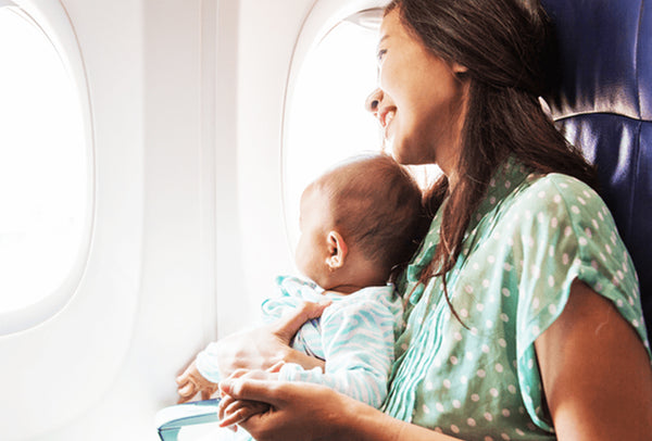 mom and baby on a plane, both looking out the window