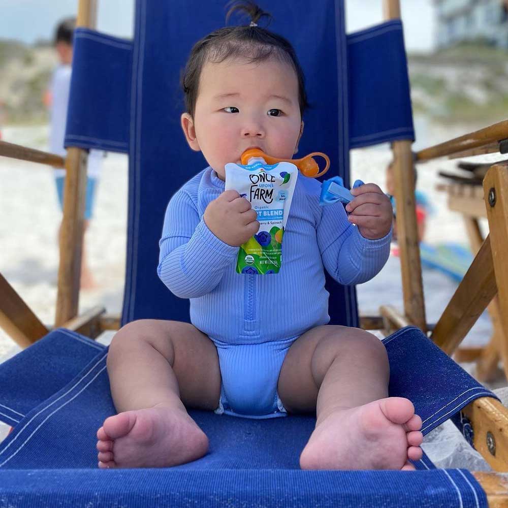 Picture of a Baby using a Choo Mee Pouch Topper on a Once Upon a Farm Pouch