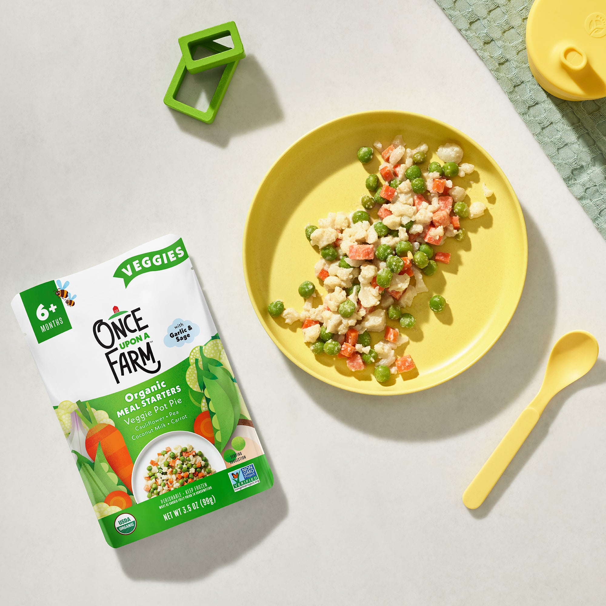 Once Upon a Farm organic Veggie Pot Pie meal packaging with a plate of food on a light surface.