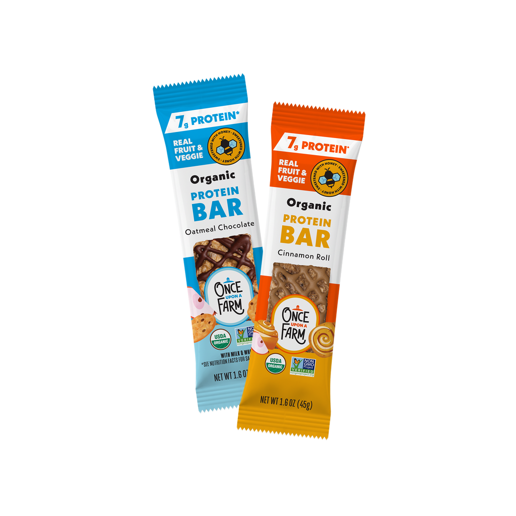 Two packaged Protein Refrigerated Oat Bar with Honey from Once Farm standing upright on a white background. The left bar is blue and labeled Oatmeal Chocolate, and the right bar is orange and labeled Cinnamon Roll.