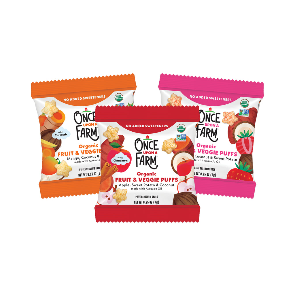 Three bags of Once a Farm Organic Fruit & Veggie Puffs arranged together on a plain white background. The front bag is red and shows apple, sweet potato, and coconut flavors, while the two bags behind it are orange and pink with mango, mango-peach, and veggie puff illustrations.