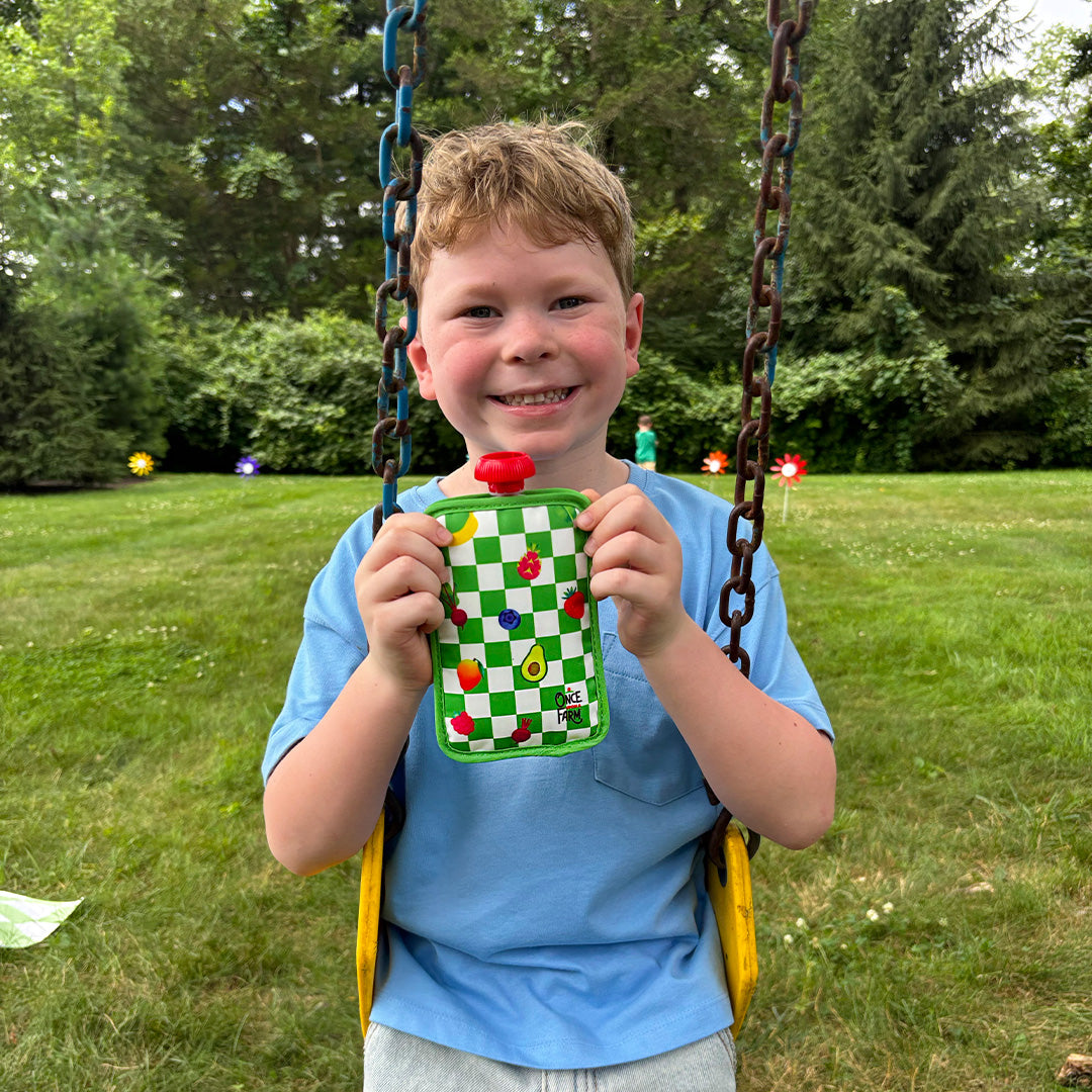 Child on swing holding green check pouch cooler